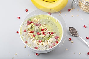 Healthy breakfast detox green smoothie with banana, kiwi, spinach, chia and pomegranate seed in a Bowl.