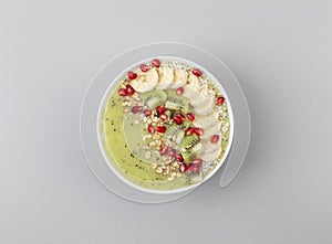 Healthy breakfast detox green smoothie with banana, kiwi, spinach, chia and pomegranate seed in a Bowl.