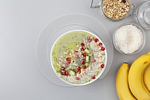 Healthy breakfast detox green smoothie with banana, kiwi, spinach, chia and pomegranate seed in a Bowl.