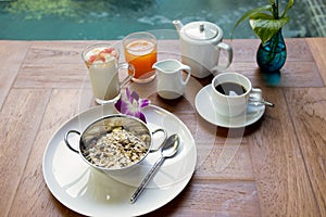 Healthy breakfast eating concept various morning food muesli, yogurt with fruit, coffee, orange juice by the pool.