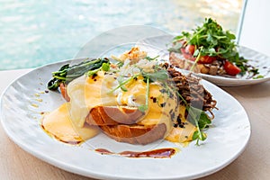 Healthy Breakfast Eggs Benedict with Whole meal Bread Toast, little salad and fresh herbs on wooden table