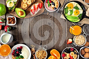 Healthy breakfast food frame with fruit, yogurt, smoothie, oatmeal, nutritious toasts and egg skillet, top view over a wood backgr