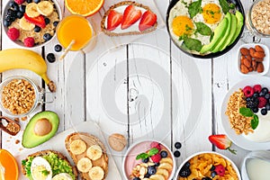 Healthy breakfast food table scene frame of fruit, yogurt, smoothie, oatmeal, nutritious toasts and egg skillet over a white wood