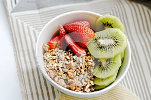 Healthy breakfast fresh granola, muesli in bowl with cereal, nuts, banana fruit, honey with drizzlier, glass of water