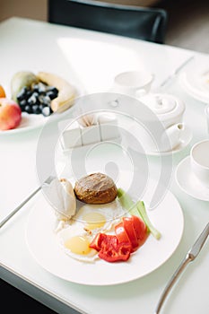 Healthy breakfast of fried eggs and fresh vegetables. Table setting with white cutlery. Selective focus.