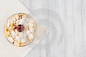 Healthy breakfast with golden corn flakes, ripe cherries, powdered sugar on white wood board top view, copy space.