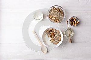 Healthy breakfast granola with greek yogurt, honey, mix nuts on white wooden background top view, copy space