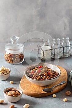 Healthy breakfast granola, muesli with berries, nuts and honey in a bowl on gray concrete background. Copy space, side view