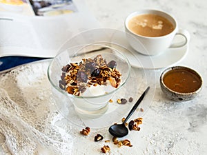 Healthy breakfast. Granola, muesli with pumpkin seeds, honey, yogurt in a glass bowl with a cup of coffee on white