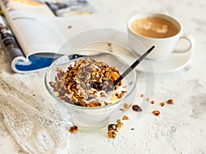 Healthy breakfast. Granola, muesli with pumpkin seeds, honey, yogurt in a glass bowl with a cup of coffee on white