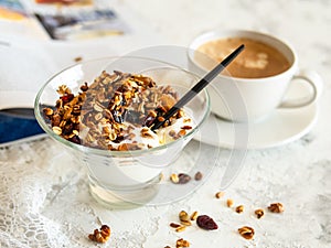 Healthy breakfast. Granola, muesli with pumpkin seeds, honey, yogurt in a glass bowl with a cup of coffee on white background.