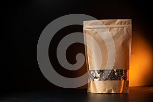 A healthy breakfast granola of various cereals in a yellow kraft paper bag. On a black background with orange light. Copy space