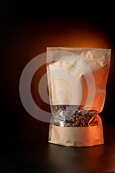 A healthy breakfast granola of various cereals in a yellow kraft paper bag. On a black background with orange light. Vertical