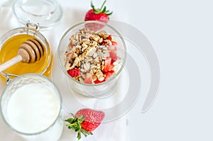 Healthy breakfast of homemade granola cereal with strawberry, nuts and fruit, honey with drizzlier background. Morning food, Diet,