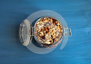 Healthy breakfast of homemade muesli in a glass jar on a blue background. View from above