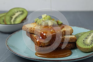 Healthy breakfast at the hotel. Toast with honey and pieces of fruit and kiwi on grey background