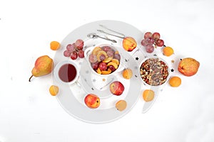 Healthy breakfast with ingredients, food for children, fruit salad with granola, grapes, pear and peaches on a bright table. The