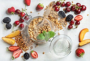 Healthy breakfast ingredients. Oat granola in jar served with slices of peach, strawberry, sweet cherries and