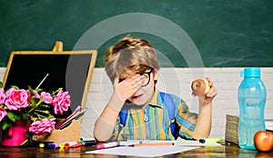 Healthy breakfast or lunch in elementary school. Little schoolboy in glasses eating apple. Kid boy in primary school