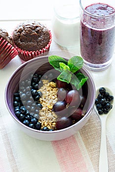 Healthy breakfast: muesli with gooseberry and blackberry, yogurt, blueberry smoothie and chocolate muffins