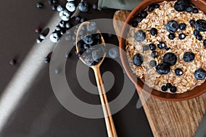 Healthy breakfast. Oat granola with fresh blueberries and currants in a clay bowl over dark grunge surface. Top view