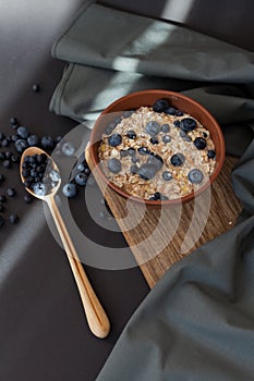 Healthy breakfast. Oat granola with fresh blueberries and currants in a clay bowl over dark grunge surface. Top view
