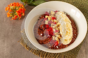 Healthy breakfast with oatmeal, cocoa, bananas, nuts and red fruits