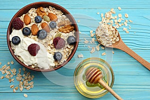 Healthy breakfast. oatmeal, honey, blueberries, raspberries and nuts on blue wooden table. Top view with copy space