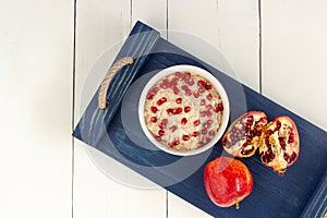 Healthy breakfast oatmeal with pomegranate,apples, seeds and nuts, overhead shot on white wooden table