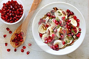 Healthy breakfast oatmeal with pomegranate, bananas, seeds and nuts