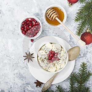 Healthy breakfast oatmeal with pomegranate, bananas, seeds and nuts, overhead scene on white marble. Top view