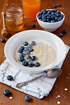 Healthy breakfast of oatmeal porridge, berries, honey and fresh juice