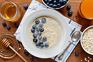 Healthy breakfast of oatmeal porridge, berries, honey and fresh juice
