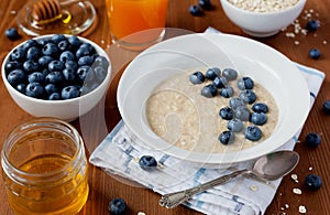 Healthy breakfast of oatmeal porridge, berries, honey and fresh juice