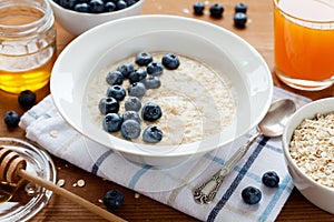 Healthy breakfast of oatmeal porridge, berries, honey and fresh juice