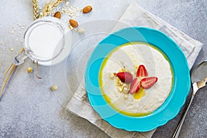 Healthy breakfast. Porridge of oatmeal with nuts, milk and fresh strawberries on stone or slate background.