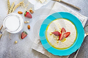 Healthy breakfast. Porridge of oatmeal with nuts, milk and fresh strawberries on stone or slate background.