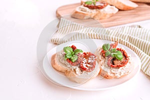Healthy breakfast recipe concept. Delicious toasts with ricotta cheese, sun dried tomatoes with olive oil topped with basil on whi