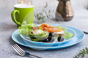 Healthy breakfast. Sandwich with smoked salmon, avocado cheese on lettuce salad leaves and coffee