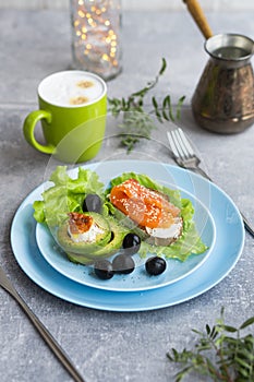 Healthy breakfast. Sandwich with smoked salmon, avocado cheese on lettuce salad leaves and coffee