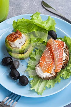 Healthy breakfast. Sandwich with smoked salmon, avocado cheese on lettuce salad leaves and coffee