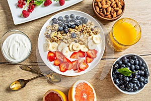 Healthy breakfast served with plate of yogurt muesli blueberries strawberries and banana.