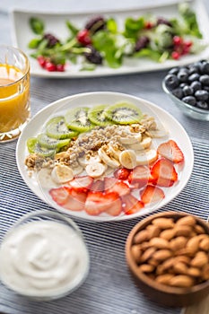 Healthy breakfast served with plate of yogurt muesli kiwi strawberries and banana