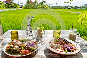 Healthy breakfast served on a vintage table with an emerald green rice field background. Concept of a healthy food and healthy