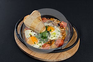 Healthy breakfast shakshuka - fried eggs, onion, bell pepper, tomatoes and spices in cast iron stewpan on old wooden plank