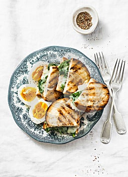 Healthy breakfast or snack - boiled farm eggs, spinach, grilled cheese sandwiches on light background