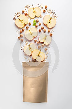 Healthy breakfast and snack concept. Top view of granola ingredients fall into paper bag on white background