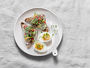 Healthy breakfast or snack - whole grain bread, feta, pickled pepper sandwiches and boiled egg on gray background