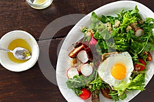 Healthy breakfast summer salad fried egg brown wooden background top view