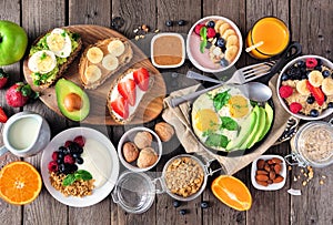 Healthy breakfast table scene with fruit, yogurts, oatmeal, smoothie, nutritious toasts and egg skillet, top view over wood